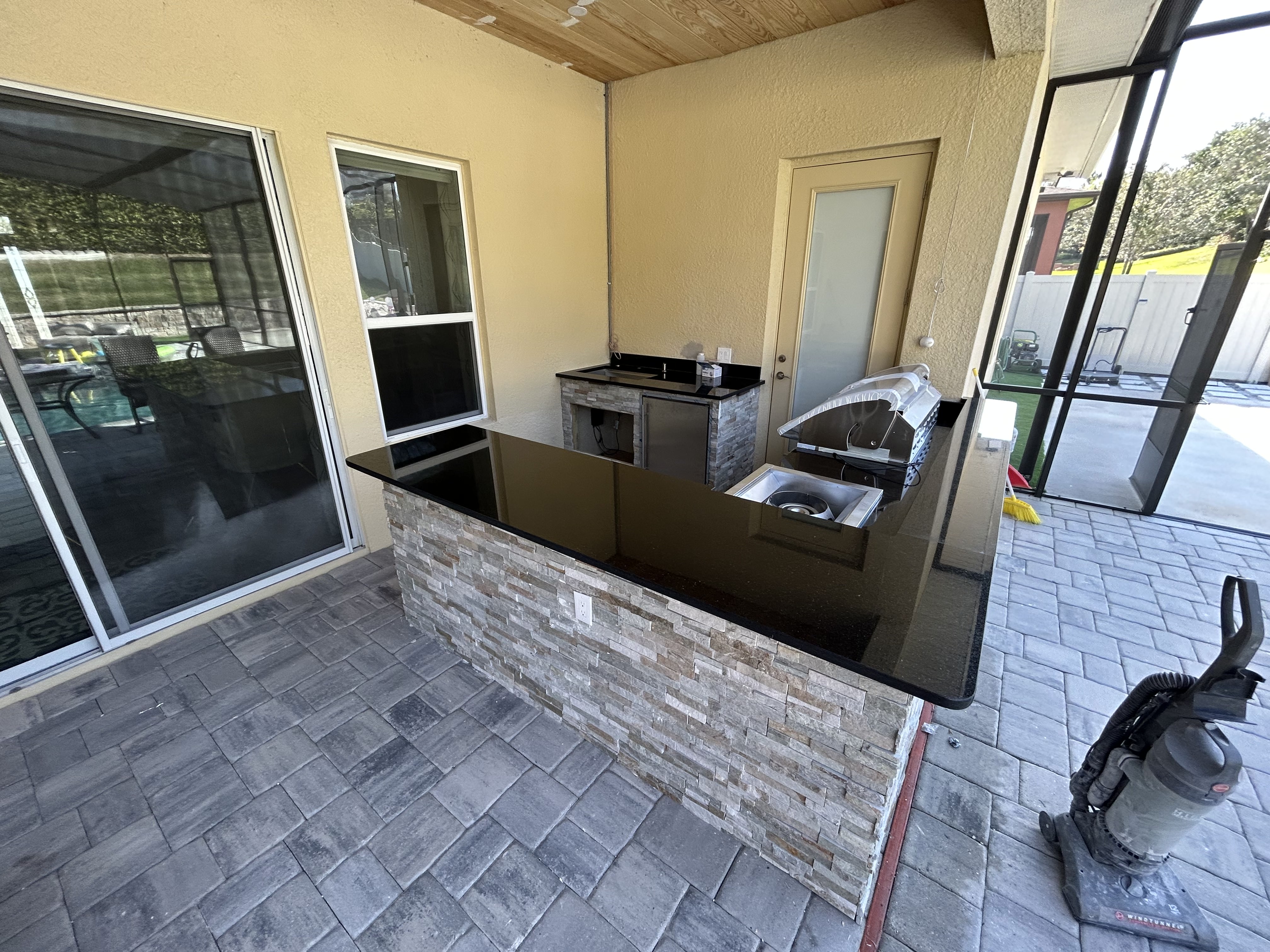 Outdoor island with stone veneer and black countertop